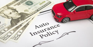 Toy car and cash on an auto insurance policy document