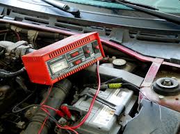 Battery charger clamped onto a car battery in the engine bay
