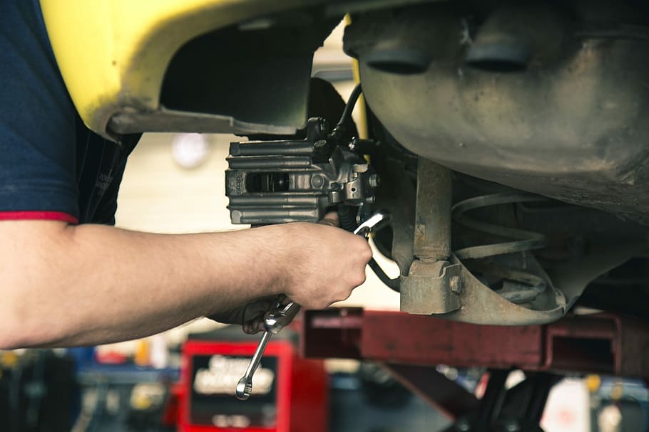 mechanic-brakes-work-car-maintenance Mechanic working on a car's brakes during maintenance