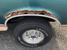 Rust hole in the wheel arch above a tyre