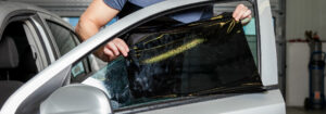 Technician applying tint film to a car window
