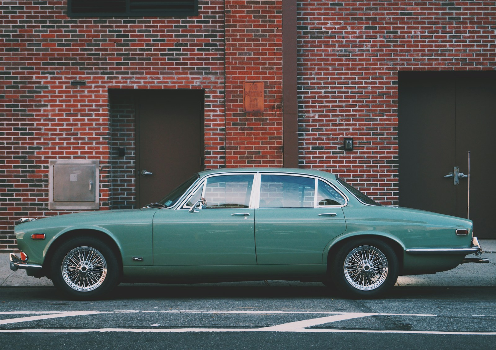 Classic Car classic teal sedan near brown brick building at daytime