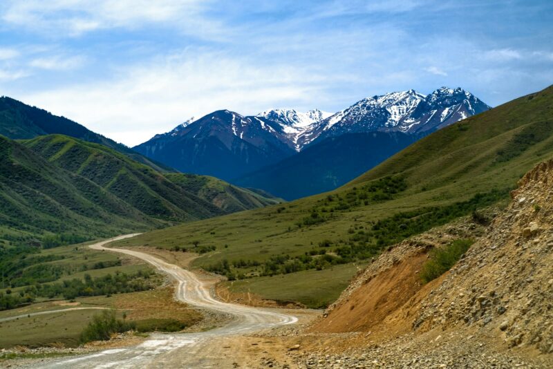 The Ultimate Road Trip Adventure Winding mountain road with scenic views of snow-capped peaks under blue skies, epitomizing adventurous road trip destinations.