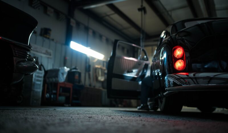 Auto Service in Progress Car taillights illuminated in a dimly lit auto repair shop.
