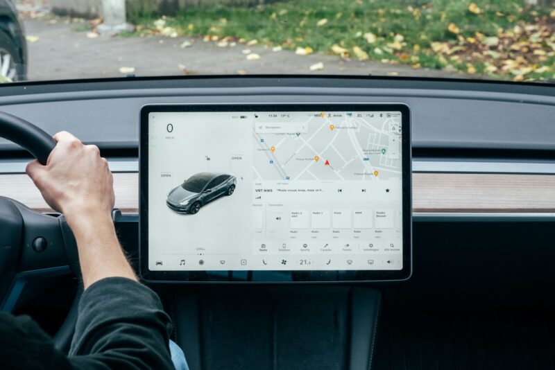 A modern car dashboard with a large touchscreen display showing GPS navigation map and vehicle settings.