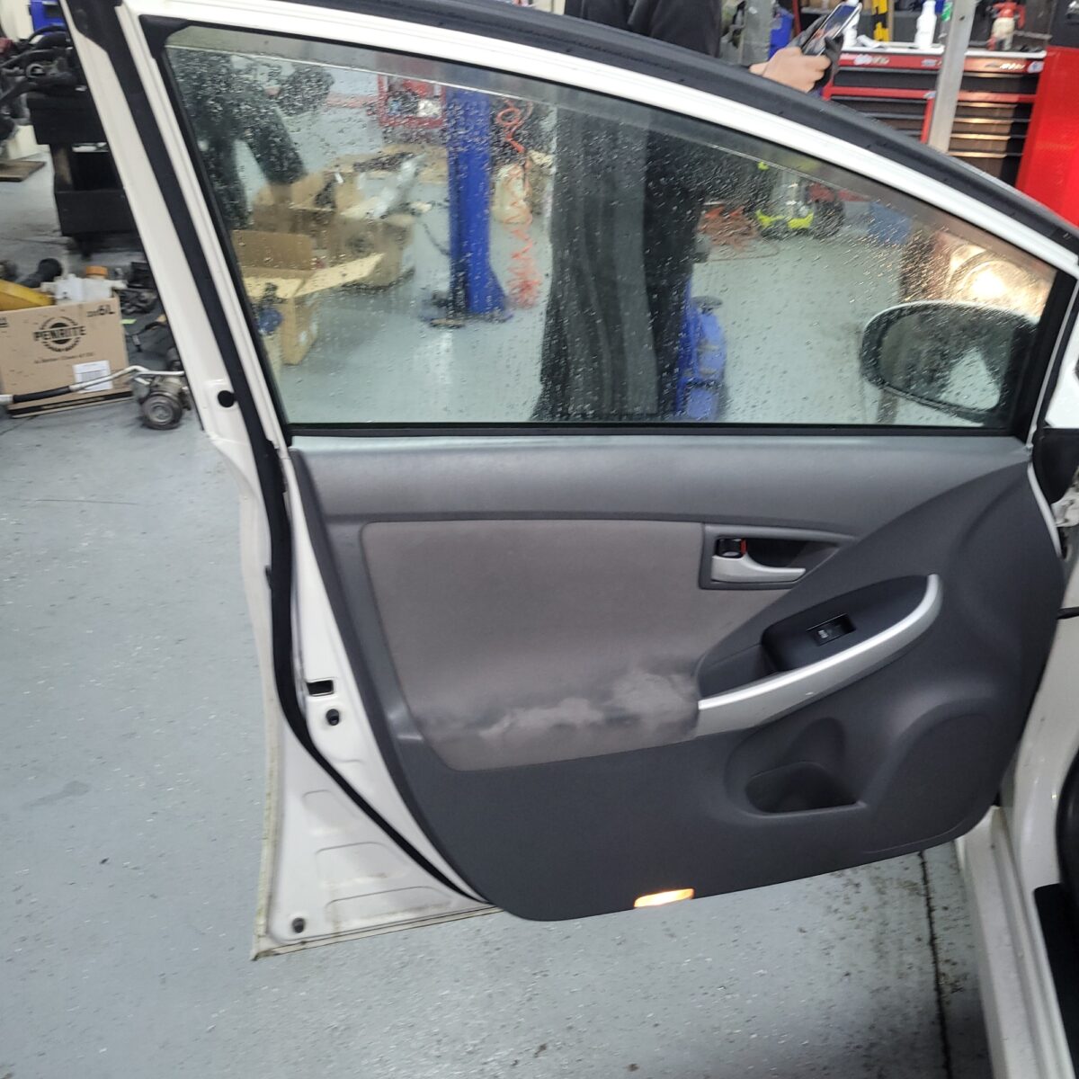 Car door with tinted window showing water droplets.