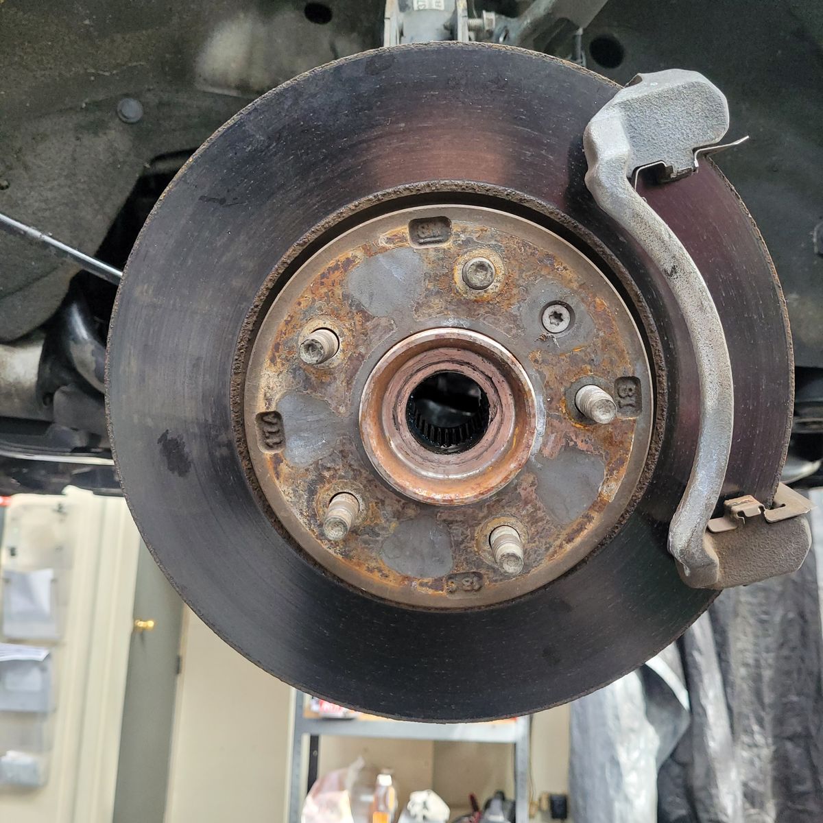 Rusty car brake rotor and caliper assembly viewed from the front wheel hub