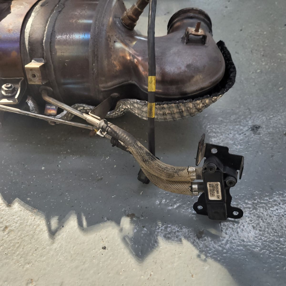 A DPF pressure sensor attached with hoses to a diesel particulate filter assembly.
