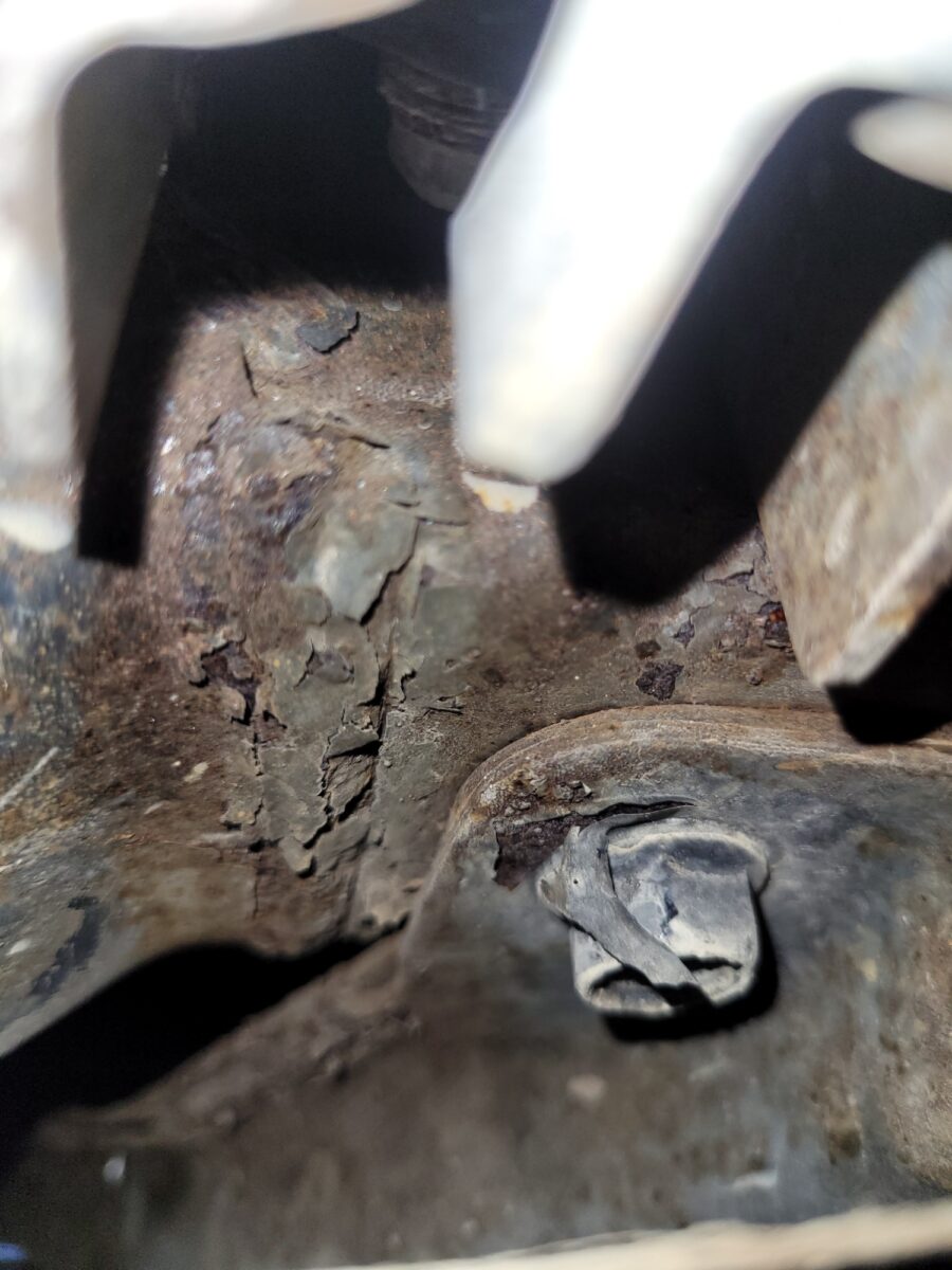 Close-up of corroded metal with peeling paint and a bolt.
