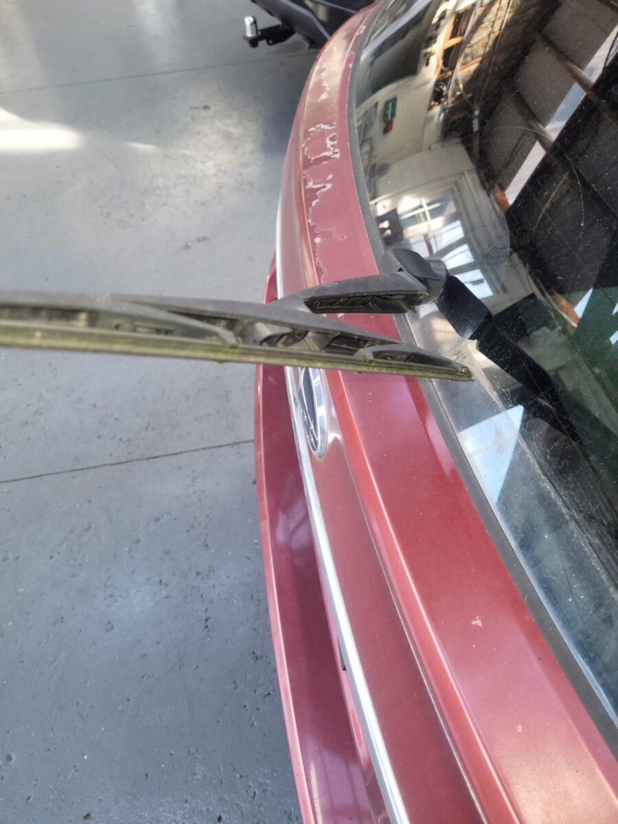 file-1750291680651-6067439 Lifted windscreen wiper on a red car