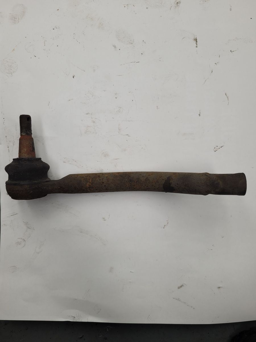 A worn and rusty tie rod for a vehicle steering system on a white background.