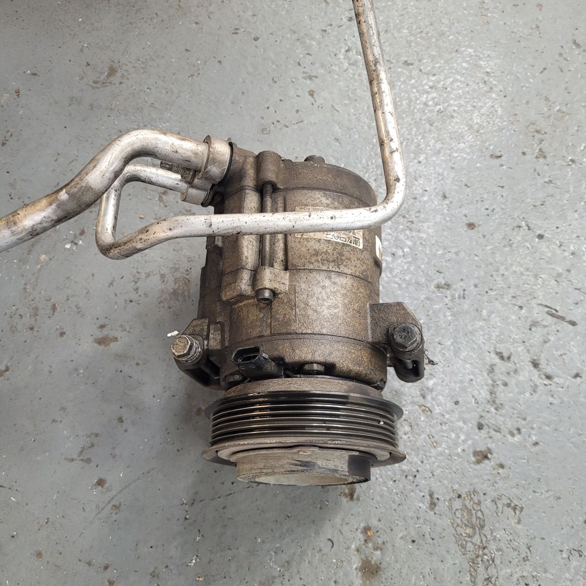 Worn car air conditioning compressor on workshop floor