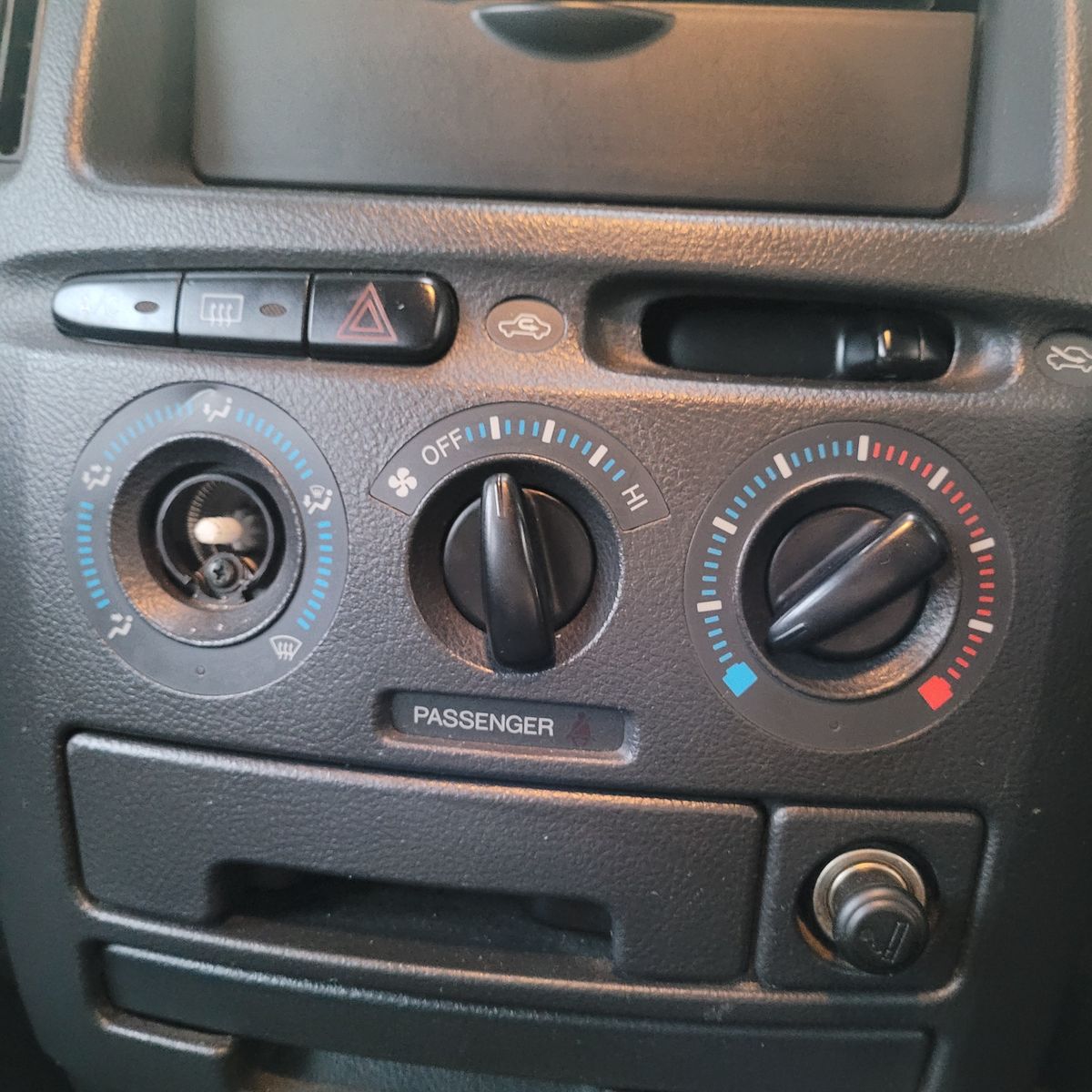 Close-up of a car dashboard air conditioning and ventilation control panel.