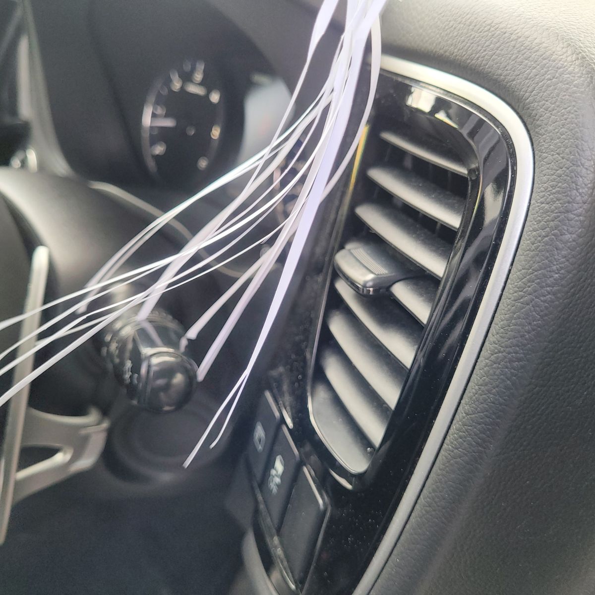 Close-up of Car Air Vent on Dashboard Car air vent with control buttons and decorative white ribbons nearby