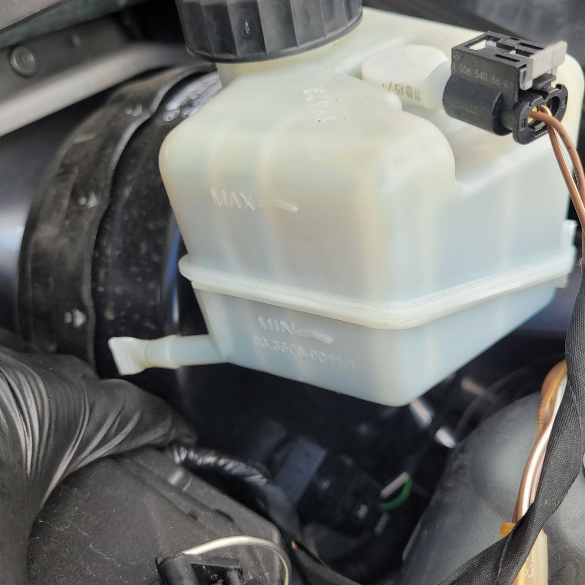 Brake Booster Vacuum Sensor and Reservoir in Engine Bay Close-up of brake fluid reservoir with vacuum sensor attached in car engine bay