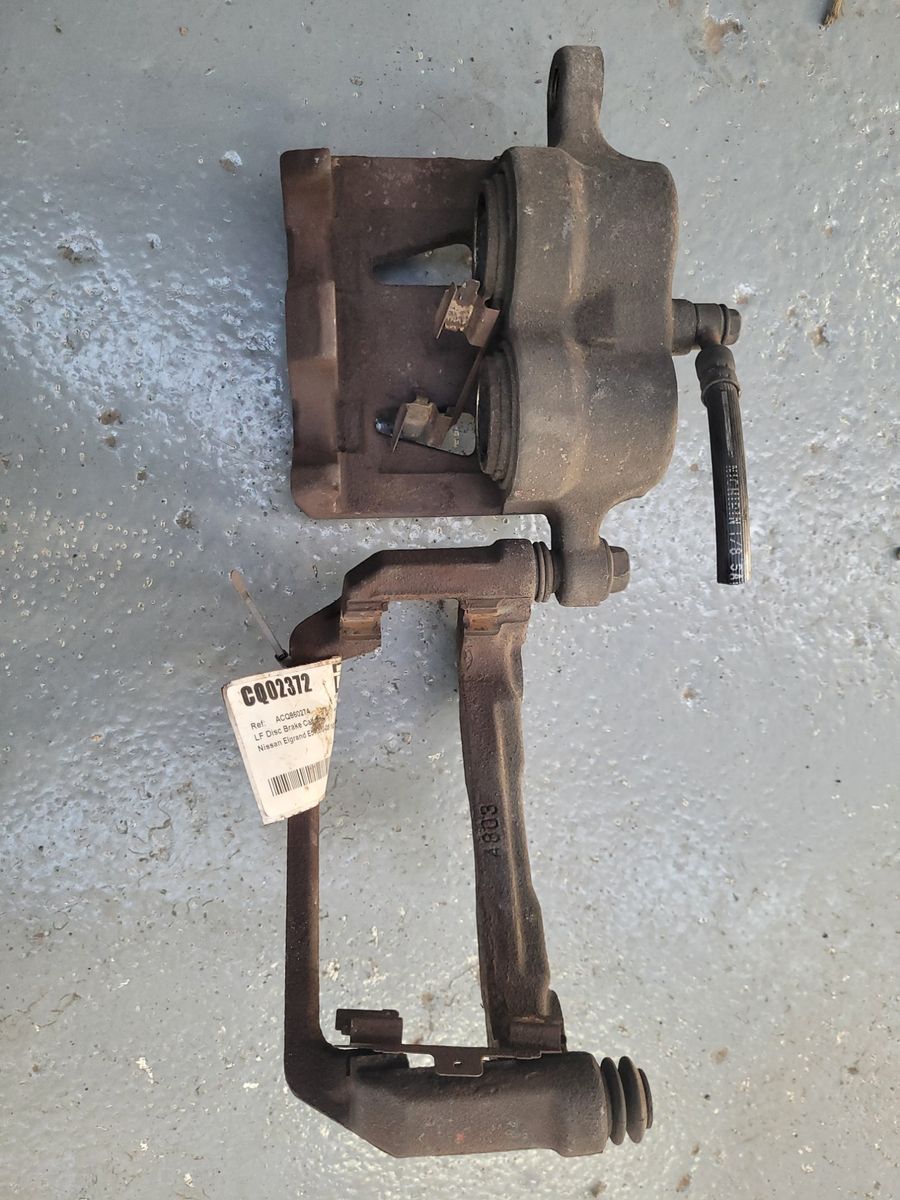 Used Automotive Brake Caliper with Bracket Dirty, used brake caliper and bracket assembly on concrete floor