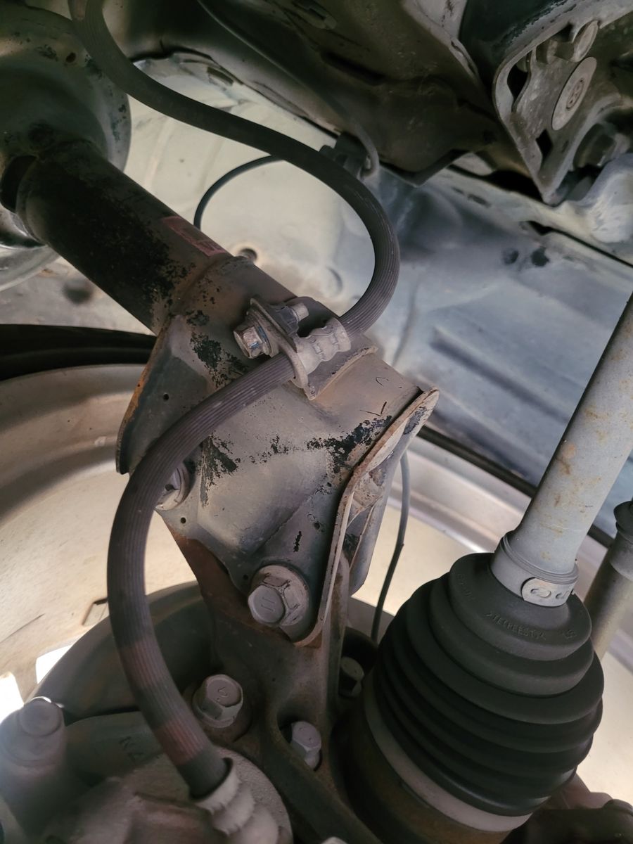 A detailed view of a car brake hose attached to a suspension component.