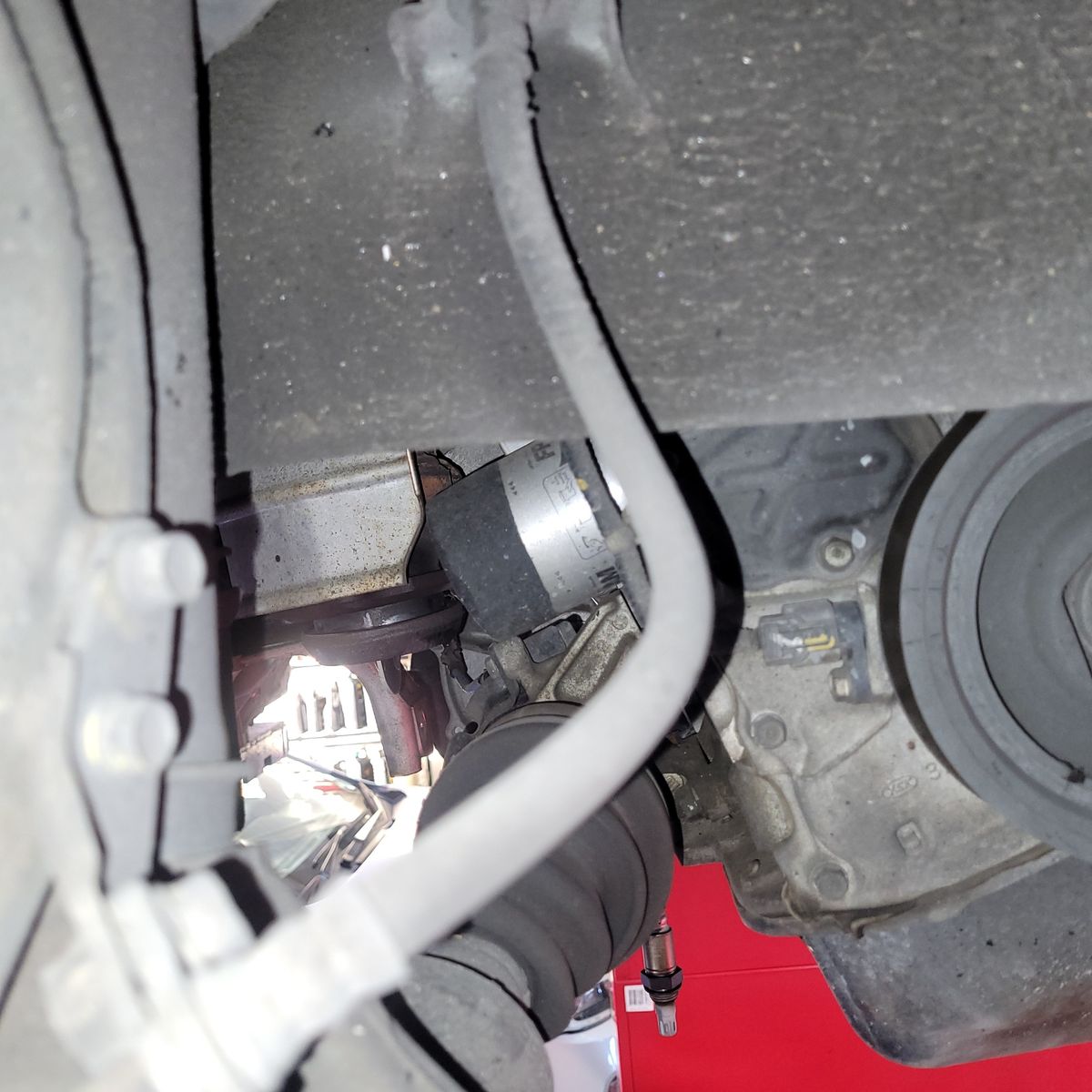 Brake hose and engine parts visible beneath a car's undercarriage.