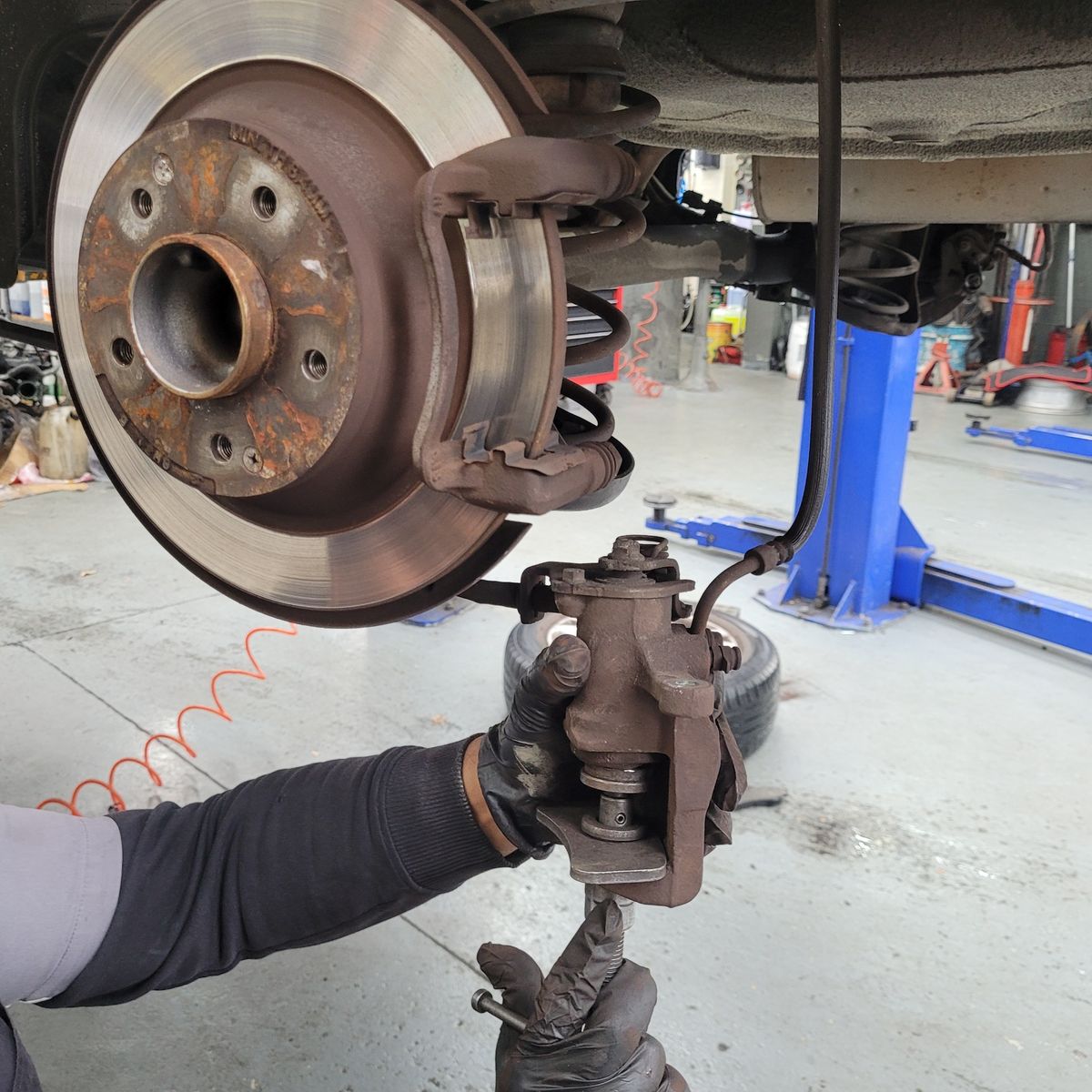 Mechanic Removing Car Brake Pads for Maintenance Mechanic's gloved hands removing brake caliper and pads from car disc