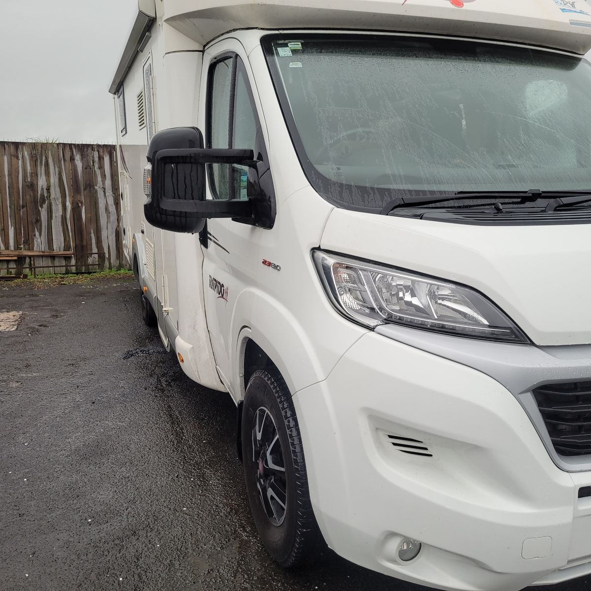 Close-up of a white camper van parked on wet asphalt