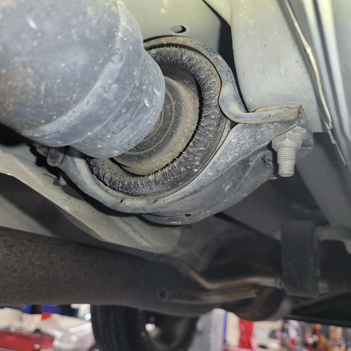 Close-up of a worn center support bearing mounted on a vehicle driveshaft