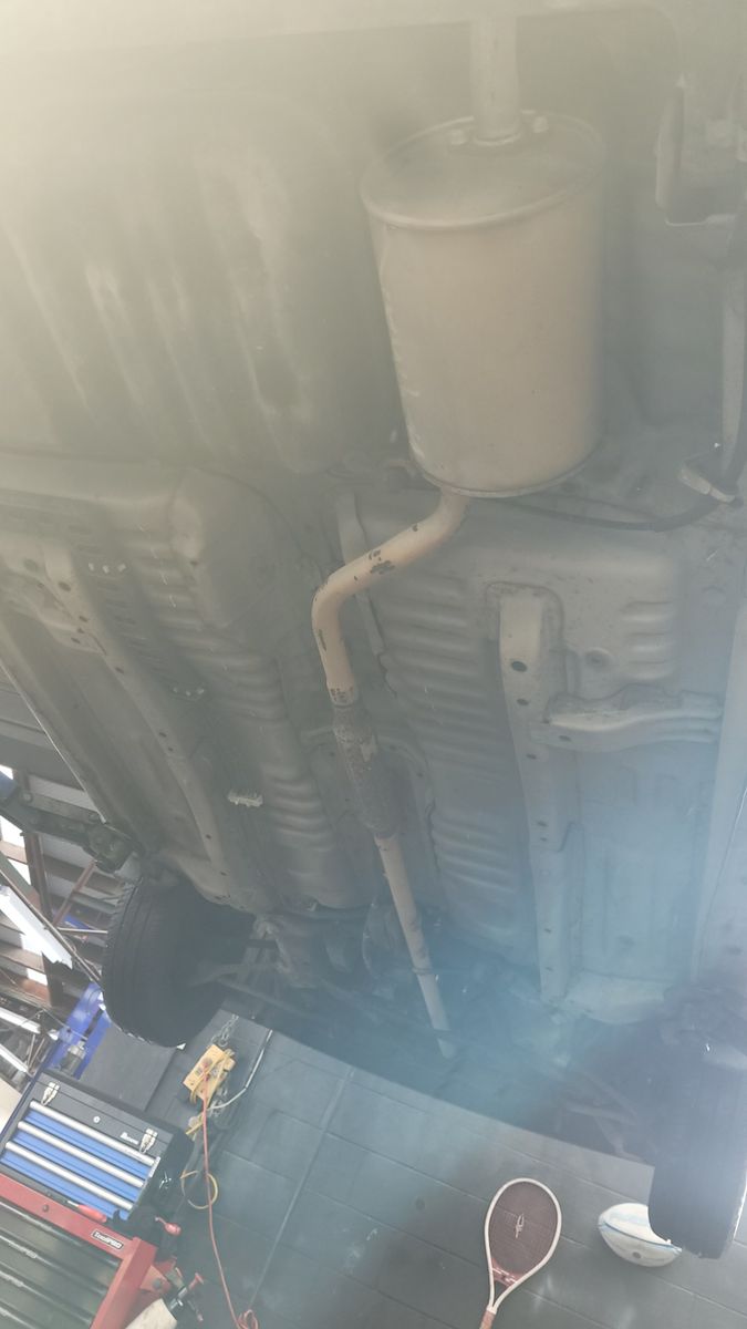 The clean underbody of a car on a lift, seen in a workshop setting