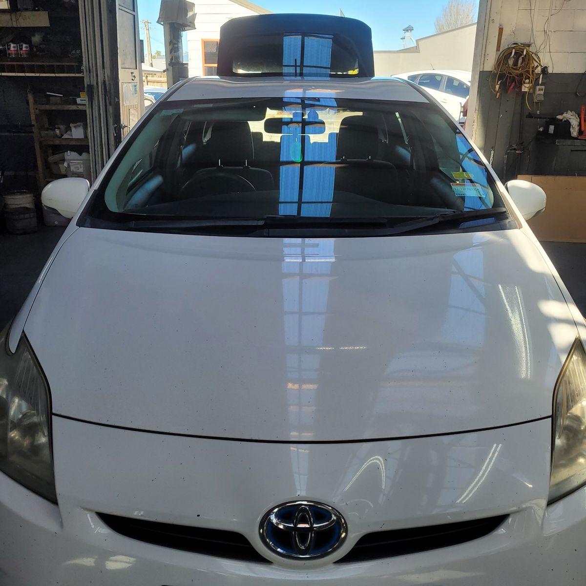 Front view of a closed white Toyota Prius bonnet inside a garage
