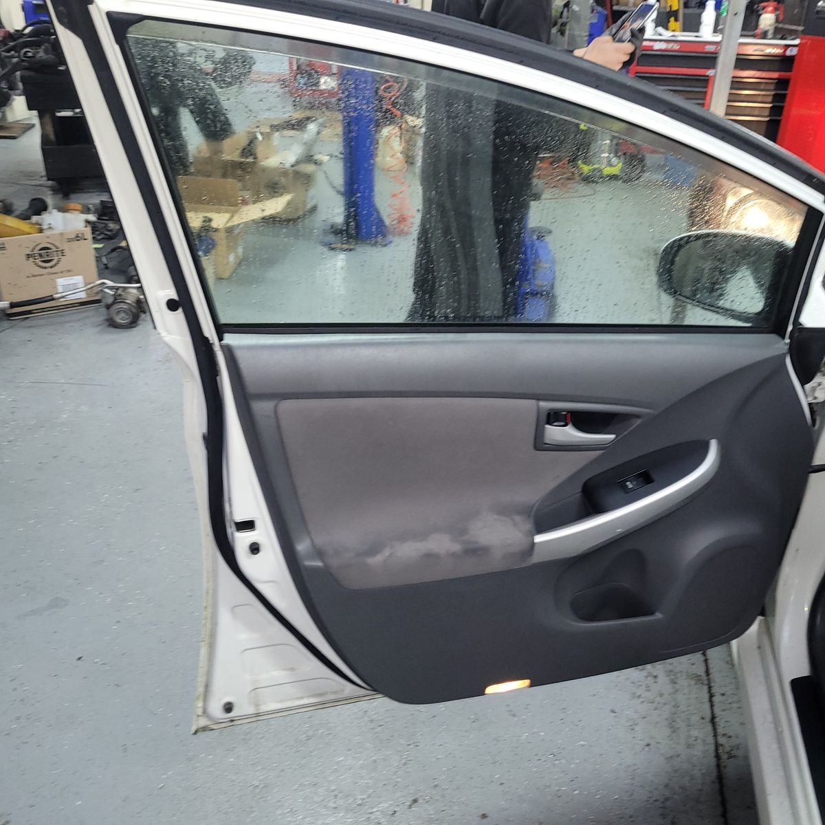 Open car door showing glass window and interior panel at mechanic workshop