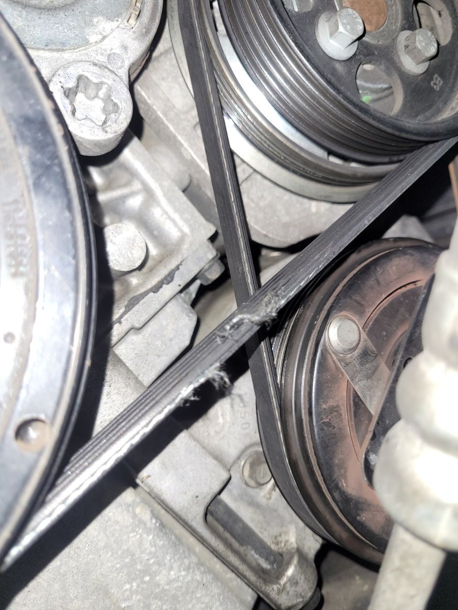 Worn and frayed drive belt on engine pulleys