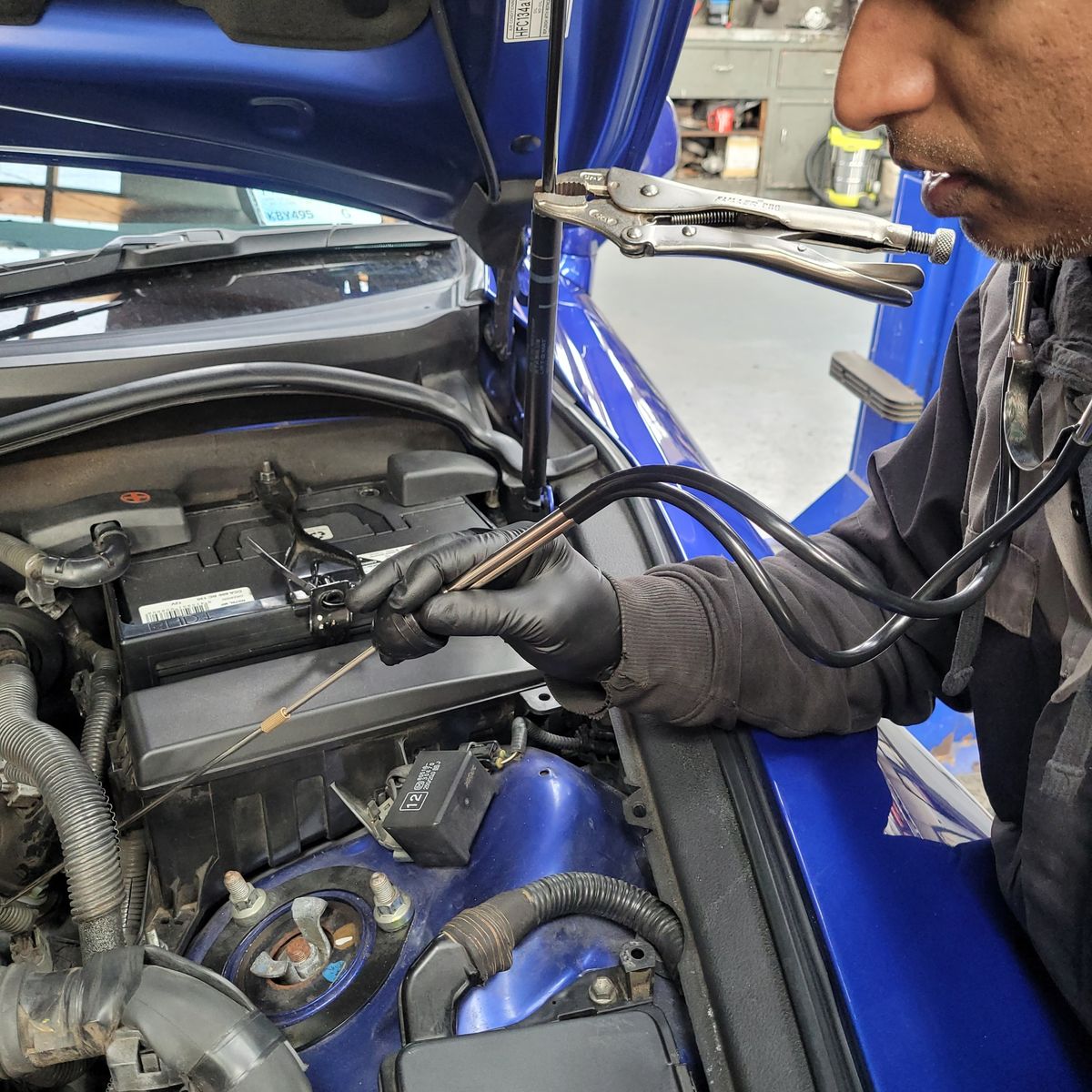 Mechanic Diagnosing Engine Noise with Stethoscope Mechanic using an automotive stethoscope to check engine noise in a car.