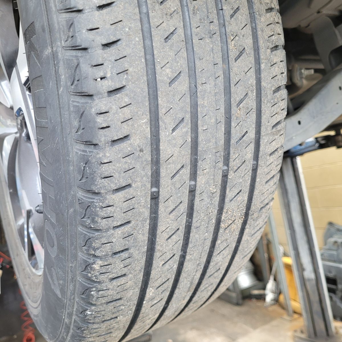 Close-Up of Newly Fitted and Balanced Car Tyre Detailed view of a new car tyre with clear tread patterns in a garage.