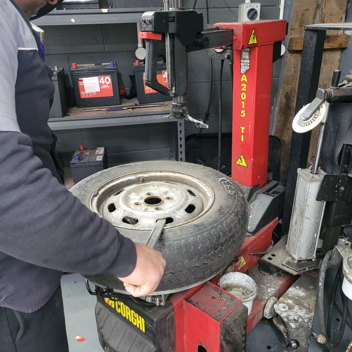 Mechanic Using Tire Fitting Machine Mechanic fitting and balancing a new tyre on a rim with a red machine