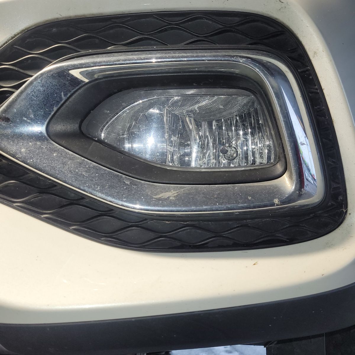 Close-Up of a Car Fog Light Car fog light with chrome and black trim, mounted on a white bumper