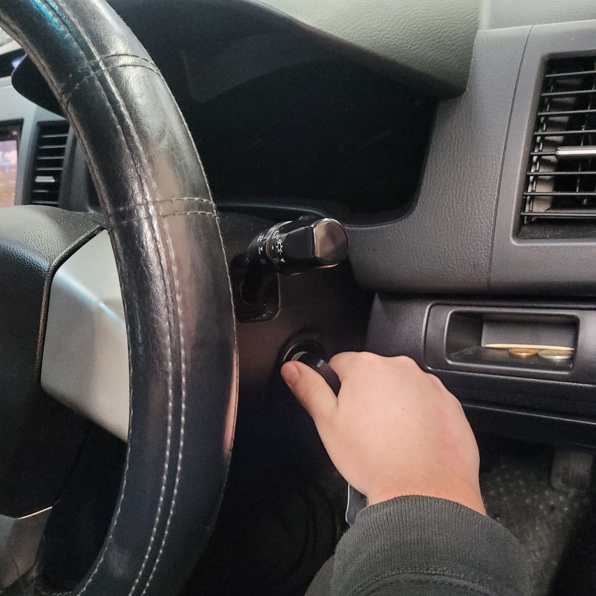 Hand Turning Car Key in Ignition Person's hand turning a key in a car ignition near the steering wheel