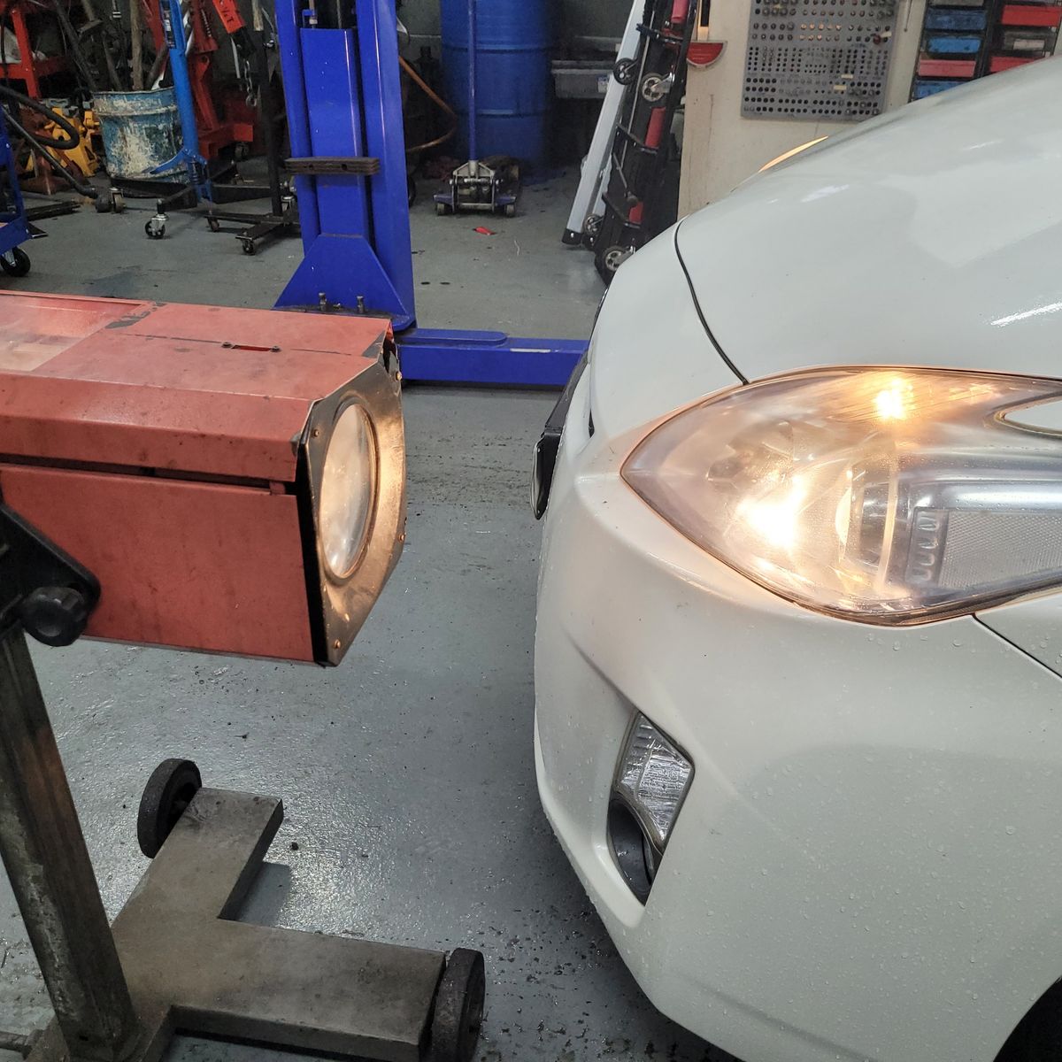 Headlight Alignment Process in Workshop Close-up of car headlight being aligned with a beam alignment tester in a garage.
