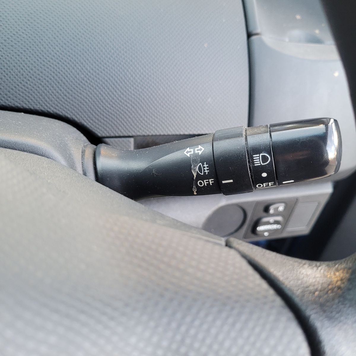 Close-up of a car headlight switch and turn signal lever