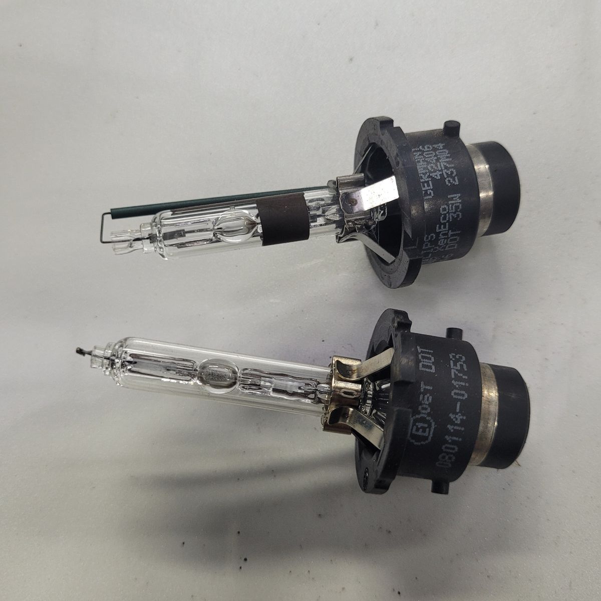 Two HID headlight bulbs with black plastic bases lying side by side