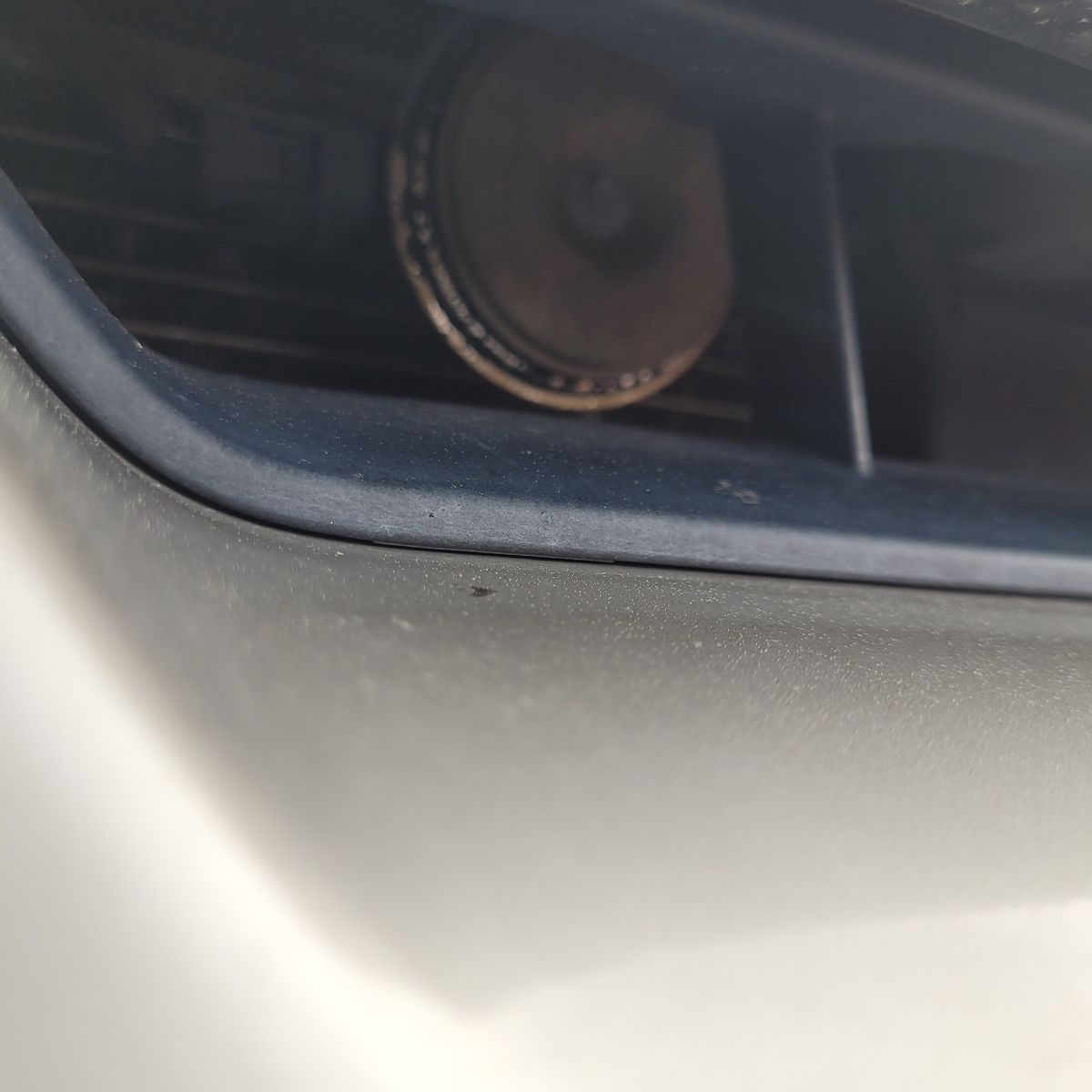 Car horn partially visible through vehicle front grille