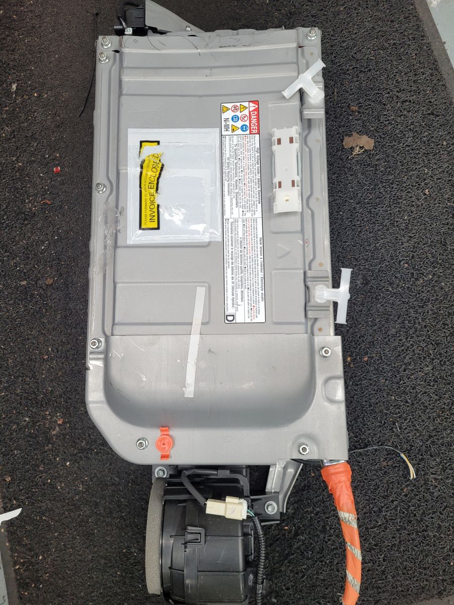 Rectangular hybrid car battery pack with warning labels and orange cable