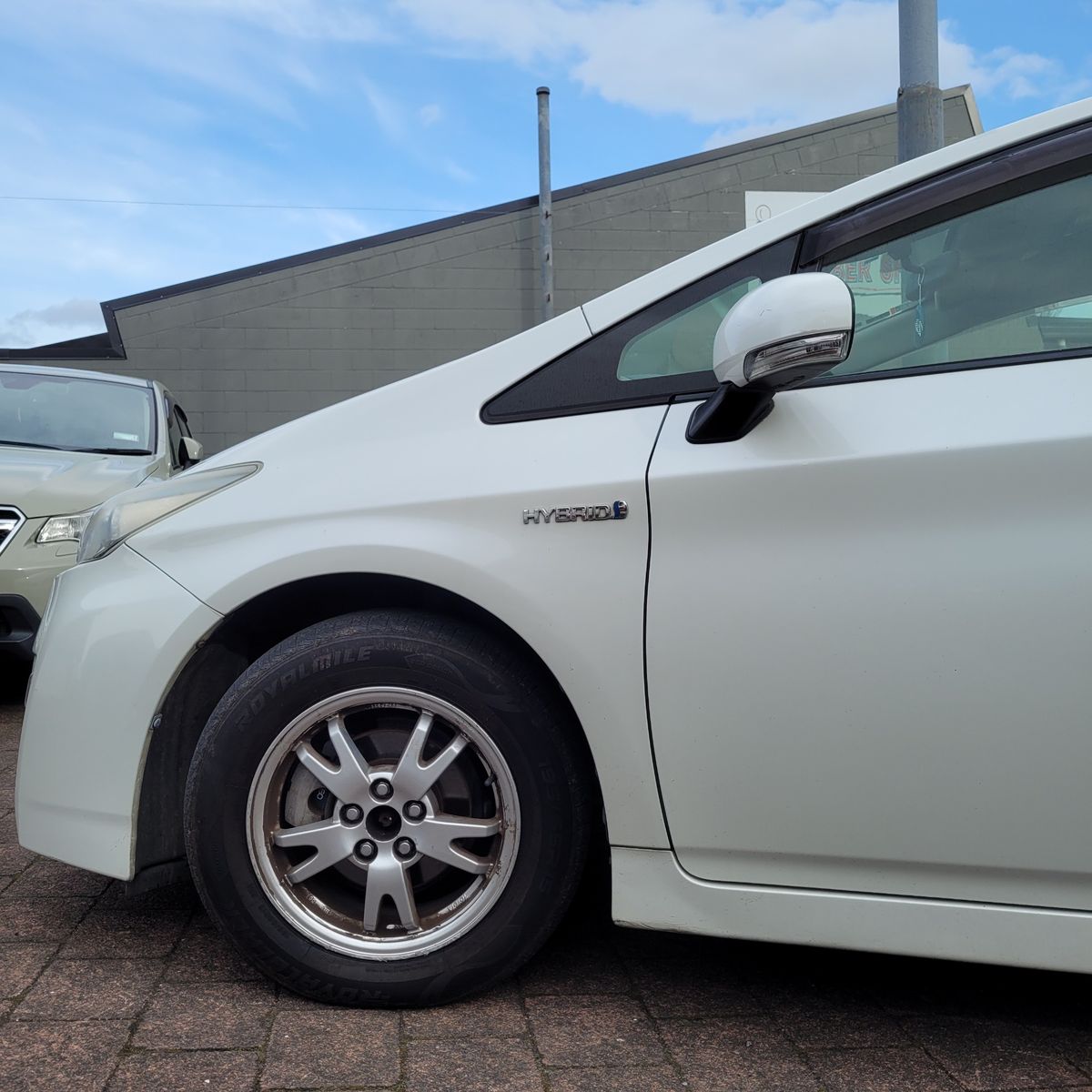 Front side view of a white hybrid car with visible hybrid badge