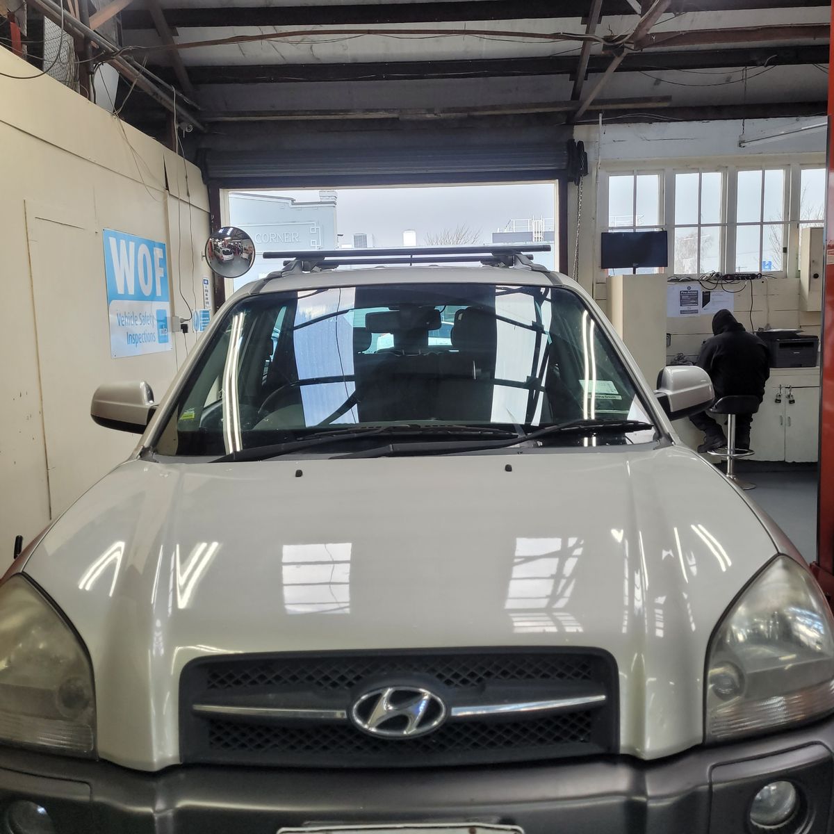 Hyundai SUV Undergoing Inspection in Garage Front view of a white Hyundai SUV parked inside a vehicle inspection garage.