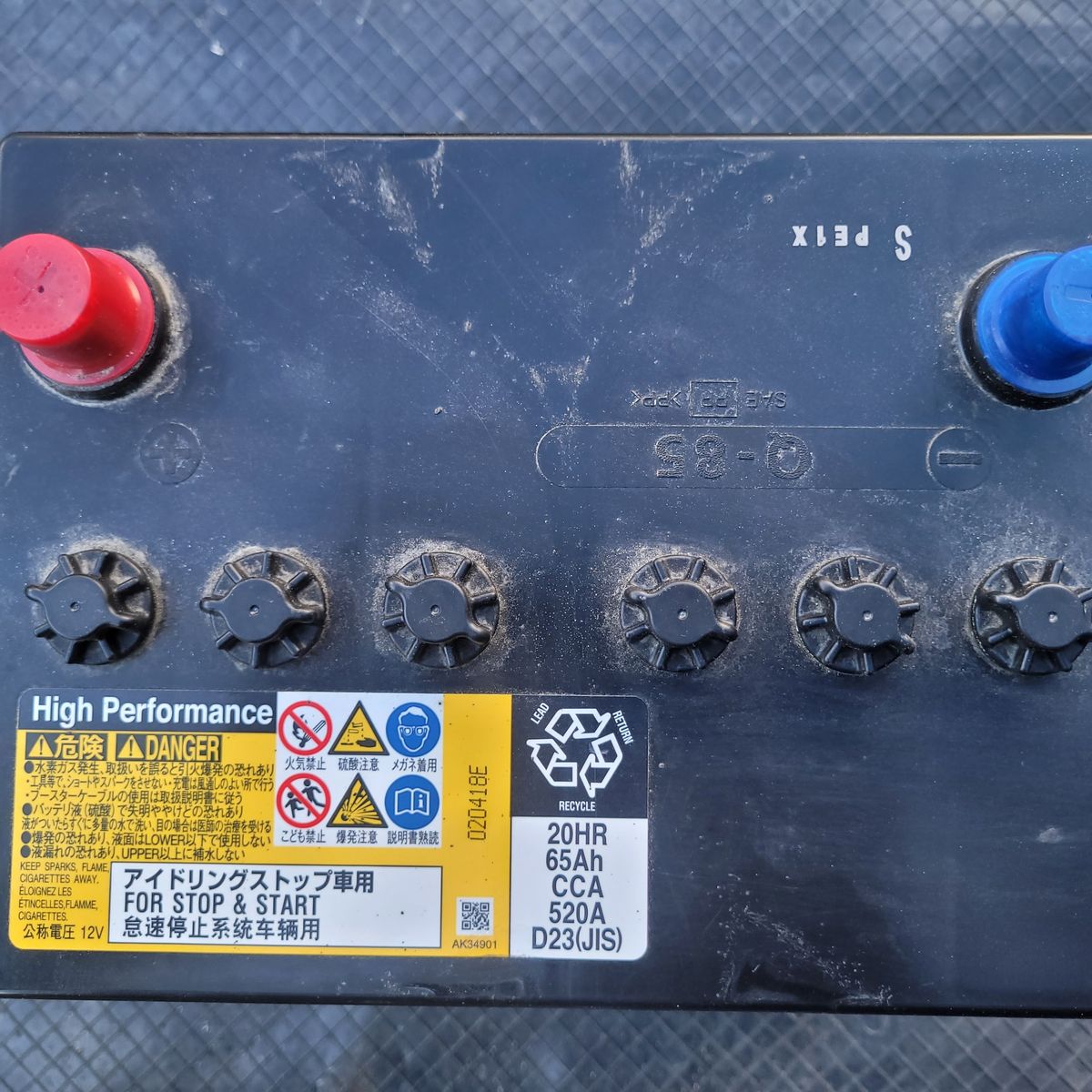 Close-up of automotive stop-start battery terminals and safety labels