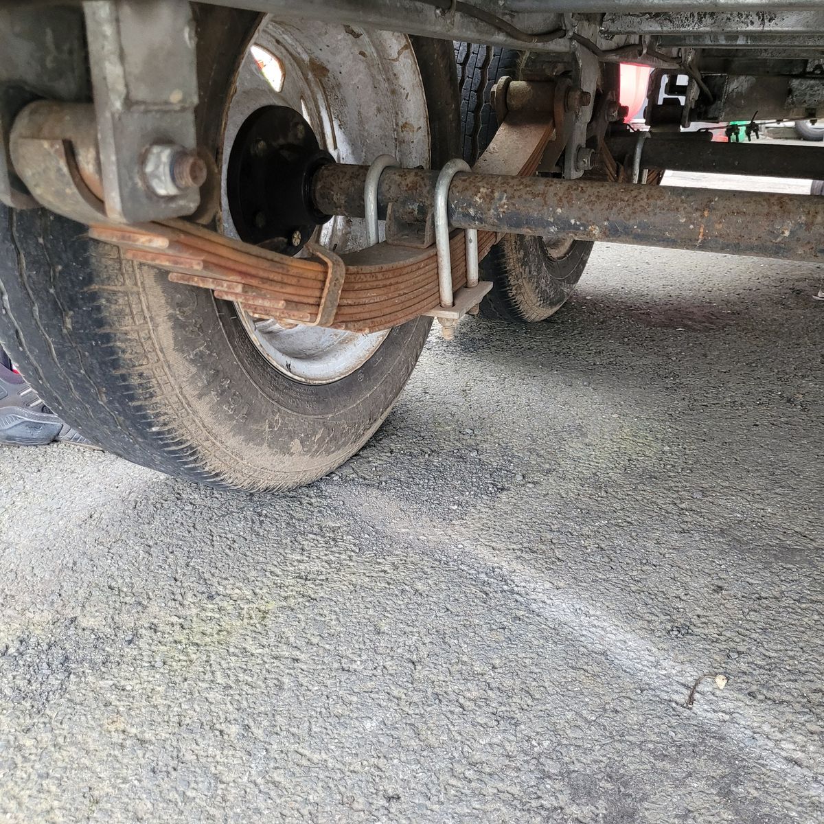 Leaf spring suspension system attached to a trailer axle and wheel