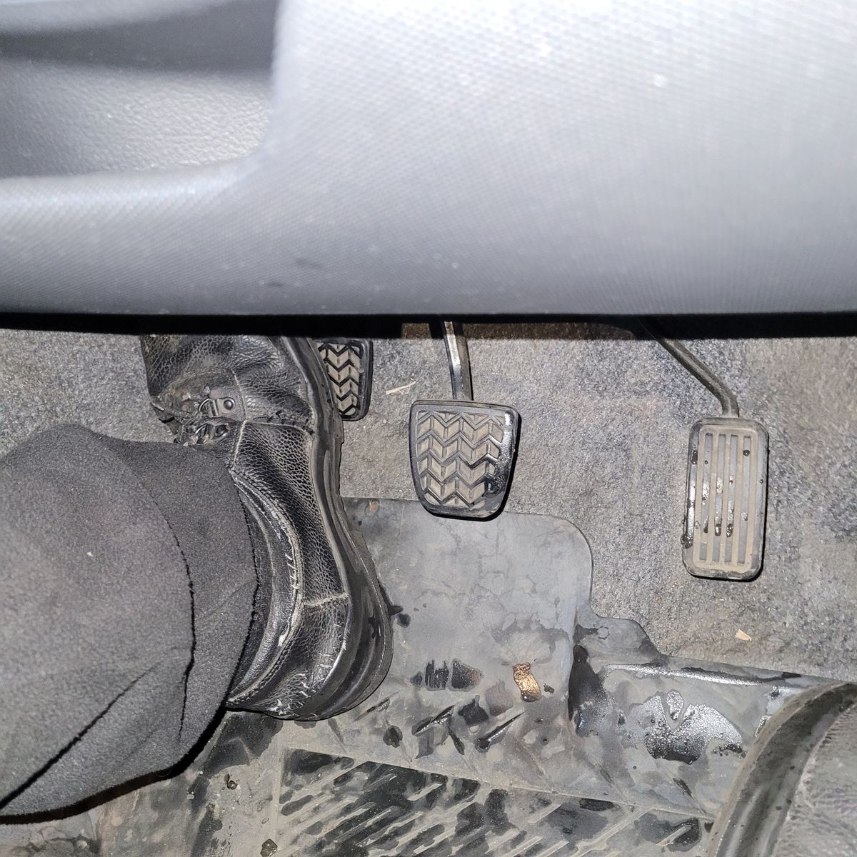 Foot pressing clutch pedal in manual car Person's foot pressing the clutch pedal of a manual transmission car