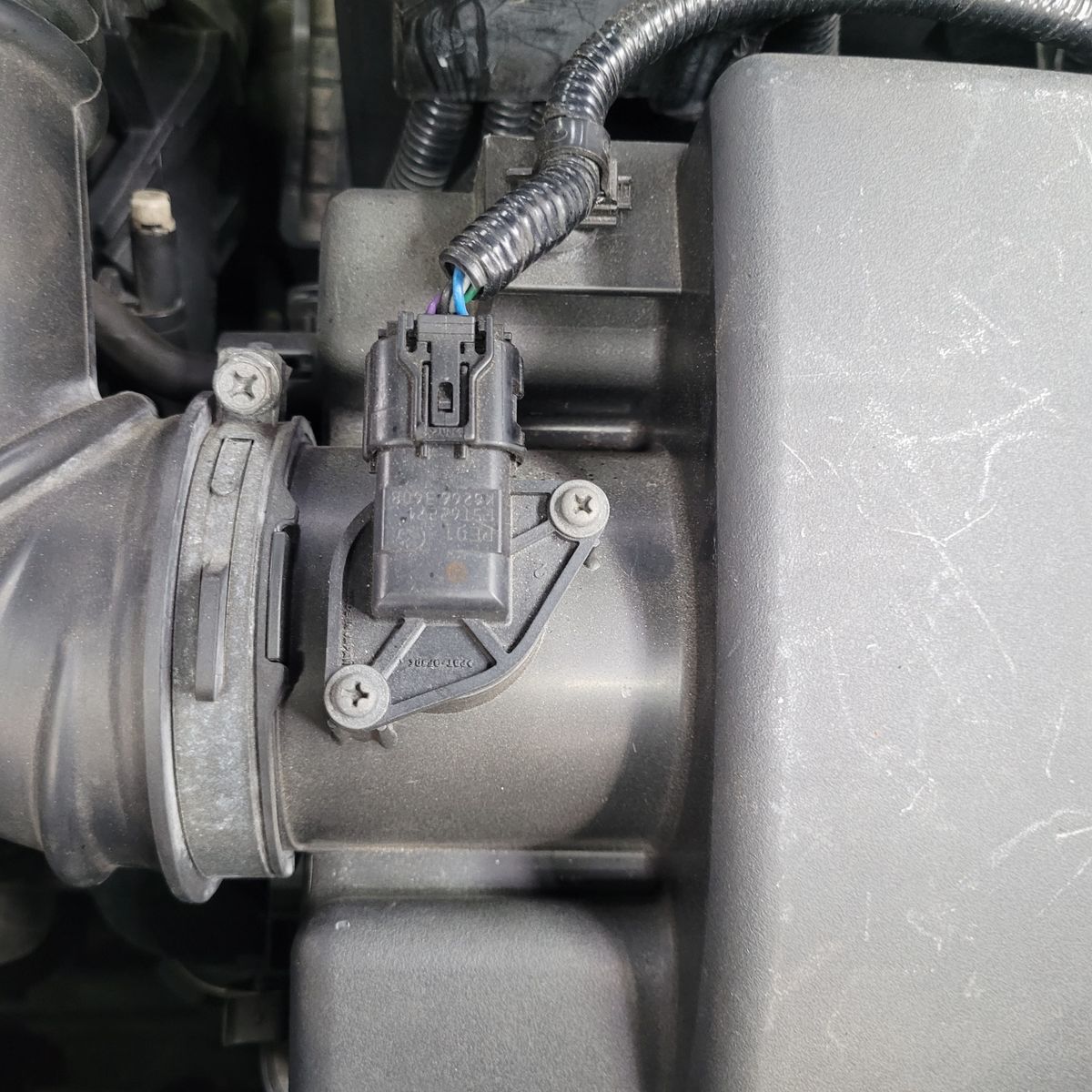 Mass Air Flow Sensor in Car Engine Close-up of a mass air flow sensor installed in a car's air intake system.