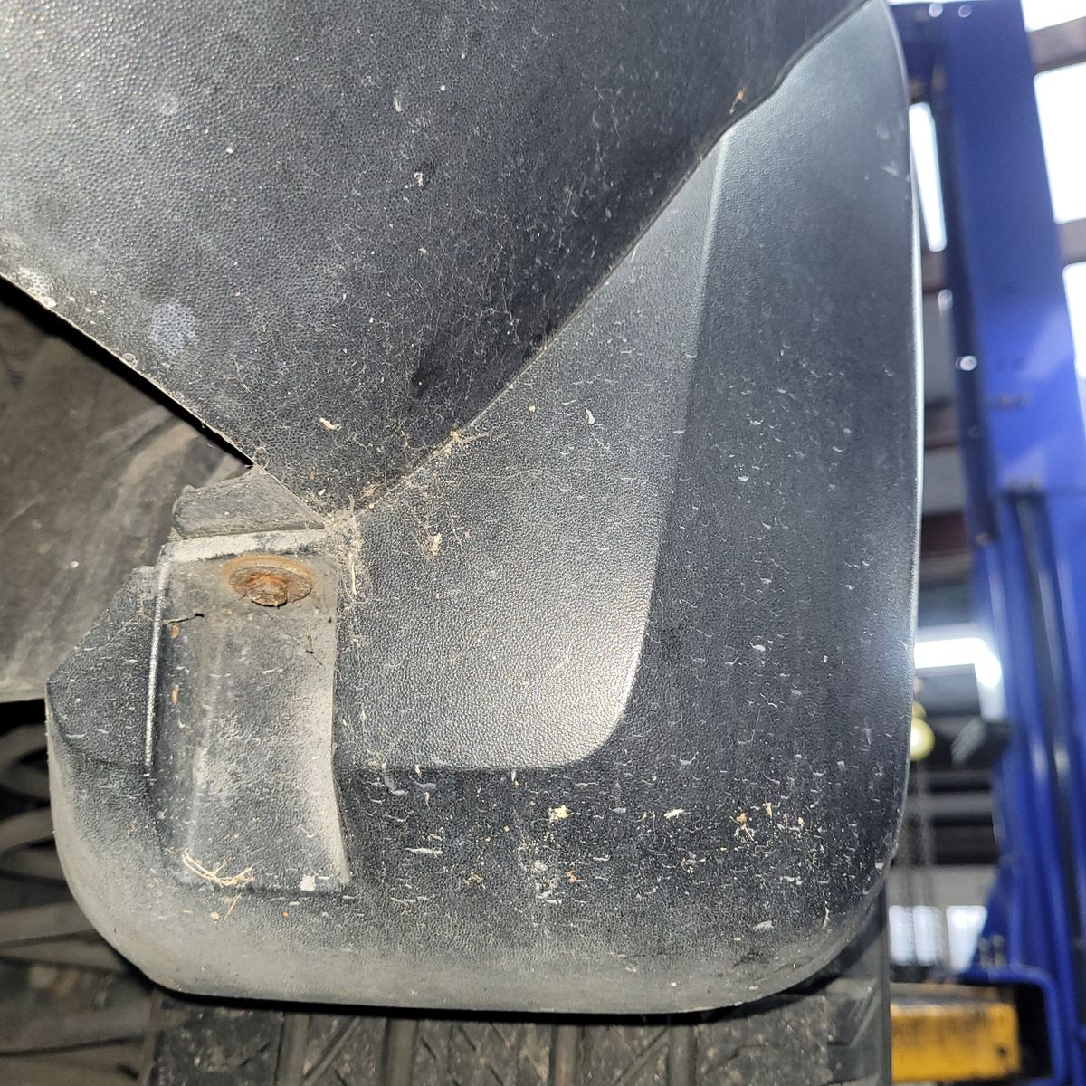 Close-Up of a Dirty Vehicle Mudflap Dirty black mudflap secured with a rusty screw on a vehicle
