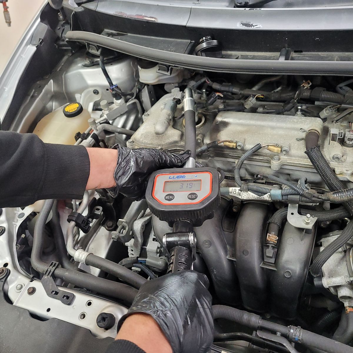 Technician Measuring Engine Pressure During Premium Service Mechanic in gloves using pressure gauge on car engine during premium service