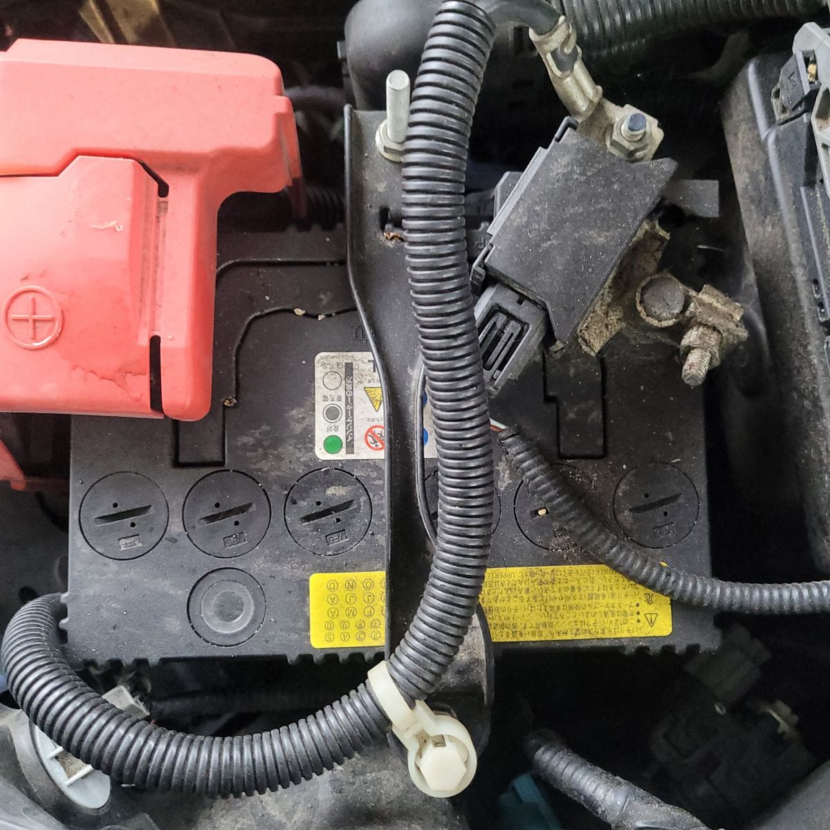 Close-up of a Car’s 12V Battery in Engine Bay Top view of a 12V car battery with visible terminals and cables.