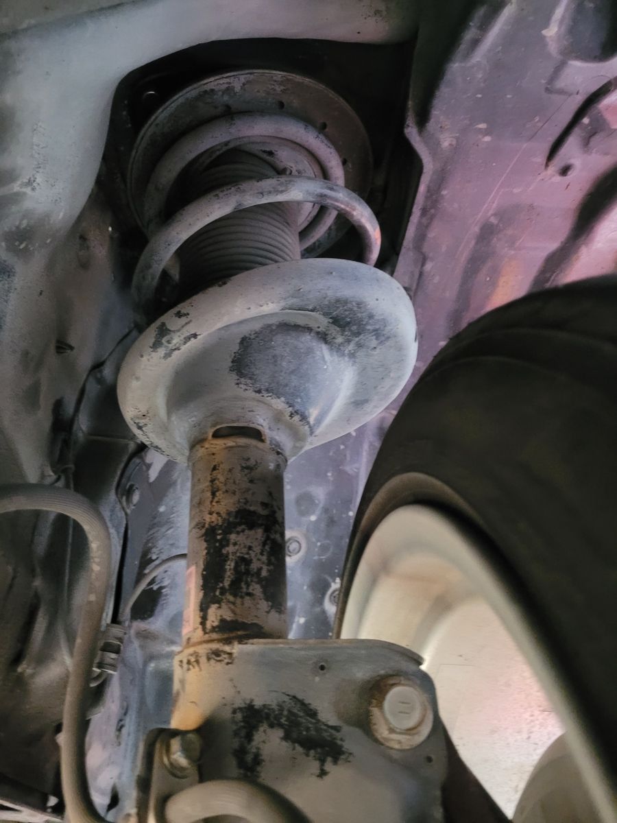 Rusty shock absorber and coil spring under a vehicle near the wheel