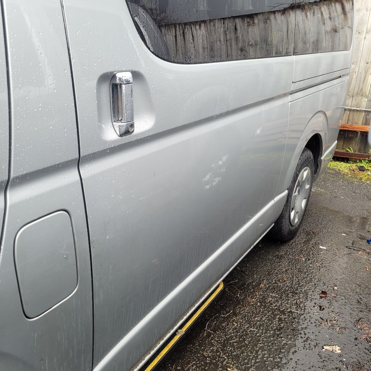Close-up of a wet silver van's sliding door and handle